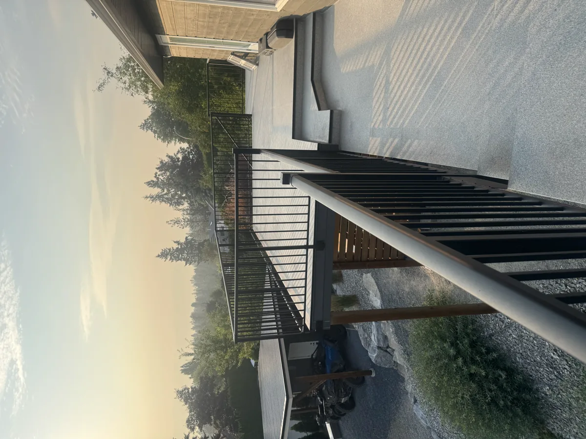 Open elevated deck with black railings and valley views before an aluminum patio cover, Kelowna